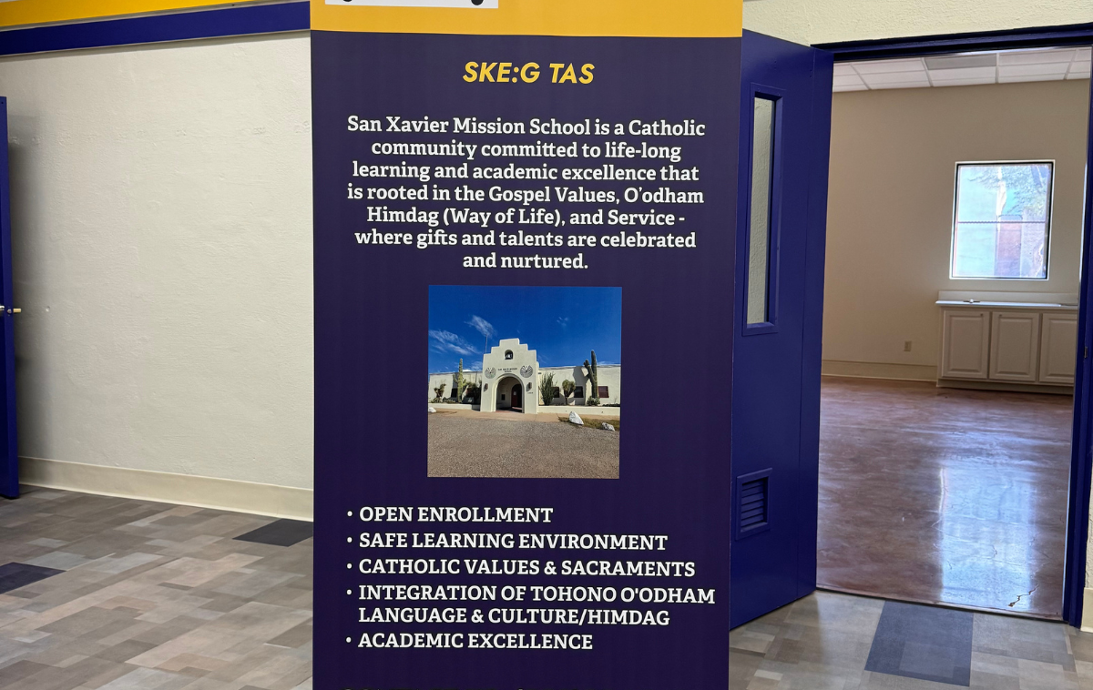 A sign reads: San Xavier Mission School is a Catholic community committed to life-long learning and academic excellence that is rooted in the Gospel Values, O'odham Himdag (Way of Life) and Service - where gifts and talents are celebrated and nurtured.