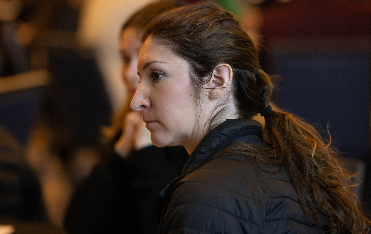 A profile view of a woman with brown eyes and brown hair in a ponytail.