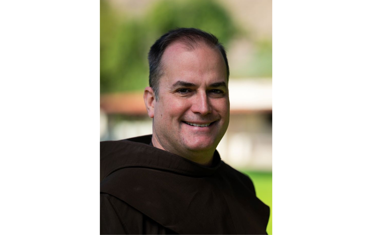 A smiling man outdoors wearing a friar habit.