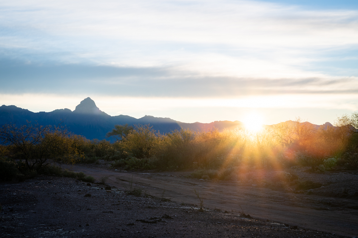 The sun sets over a desert mountain range.