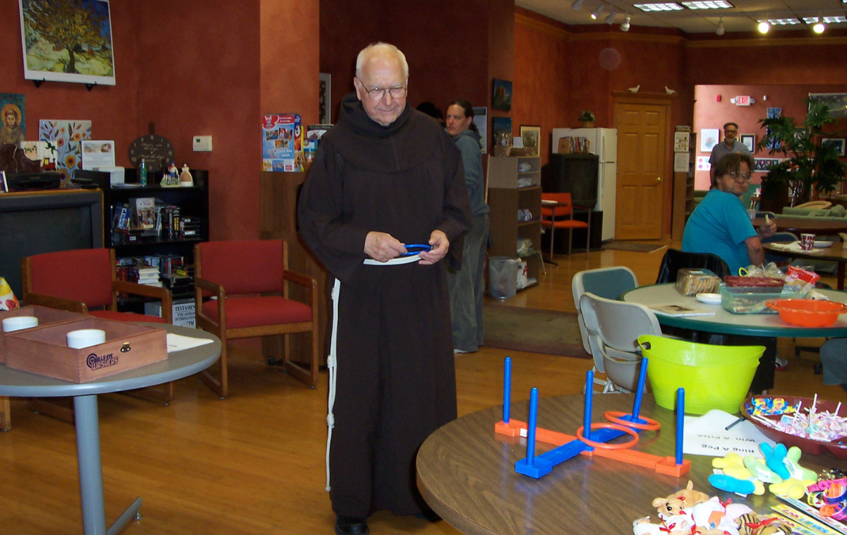A friar plays ring toss with guests.