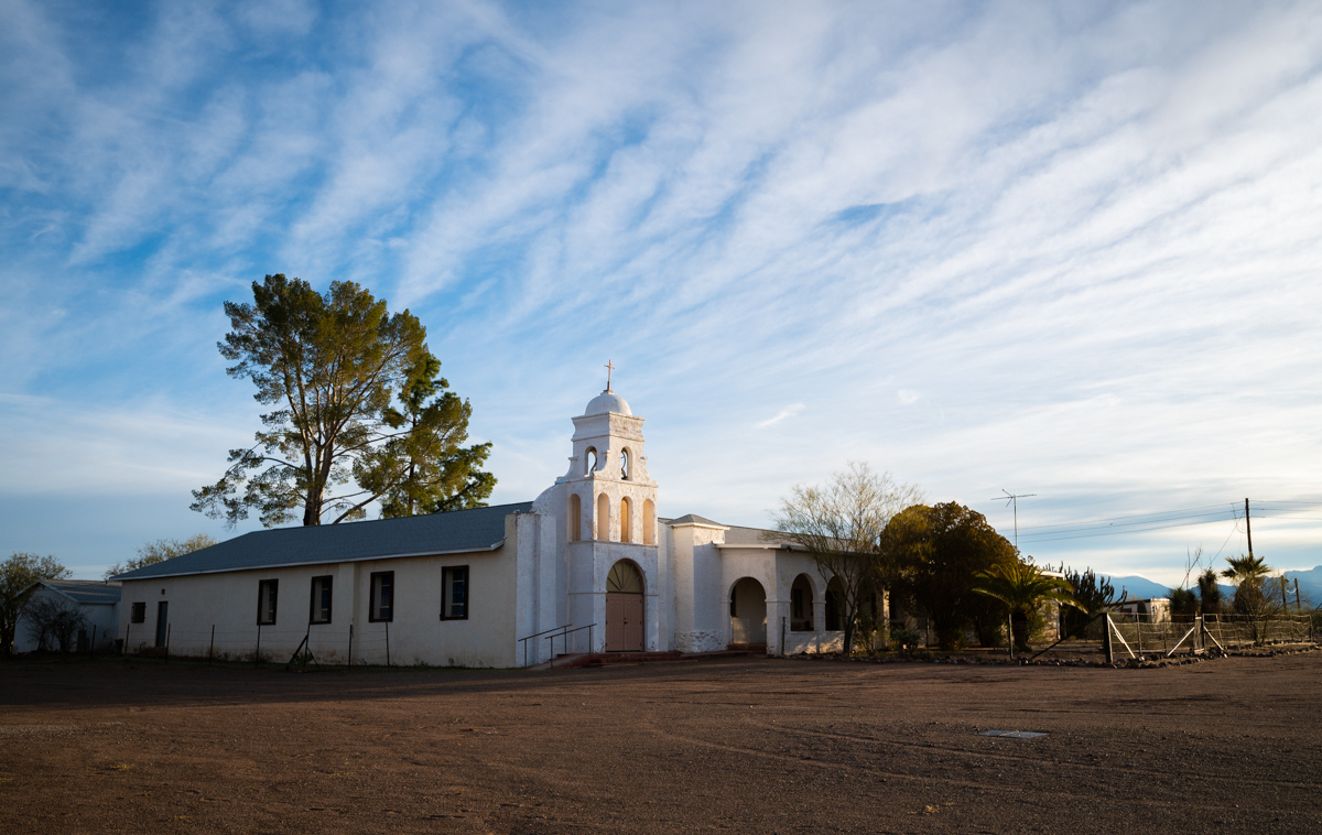 A small white mission-style church sits in the middle of the Arizona desert