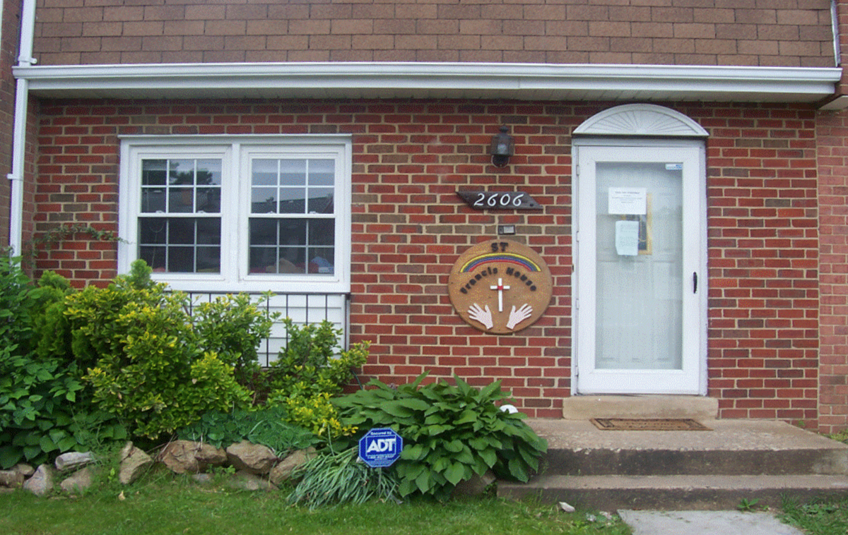 The exterior of a small brick townhouse with a welcoming sign that reads 