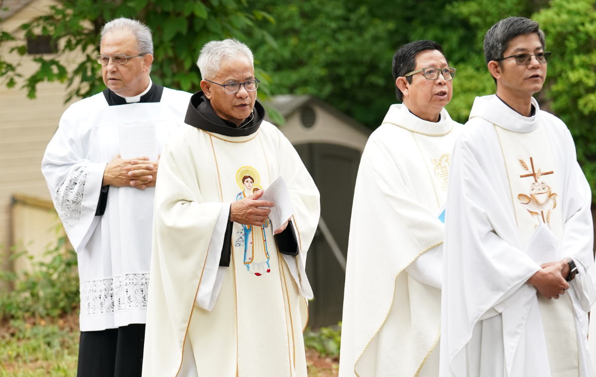 Br. David Phan walks as part of a procession of Vietnamese clergy during a feast day celebration. Br. David is wearing white vestments embroidered with Our Lady of La Vang holding the infant Jesus.