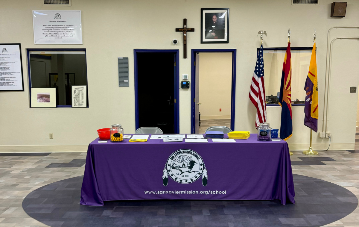 A table with a purple tablecloth with the school's logo. It is covered with informational material for student.