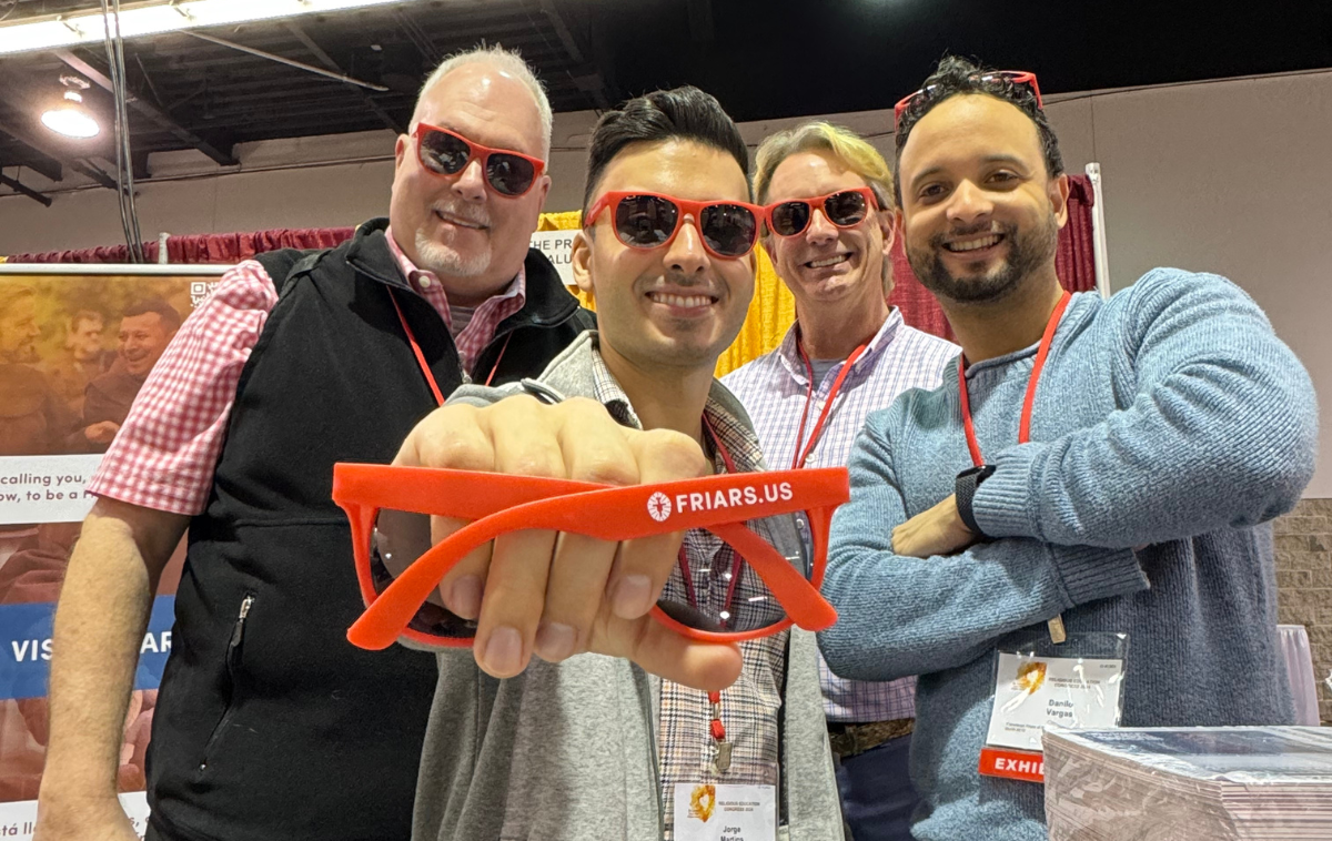 Four men wearing orange sunglasses that have 