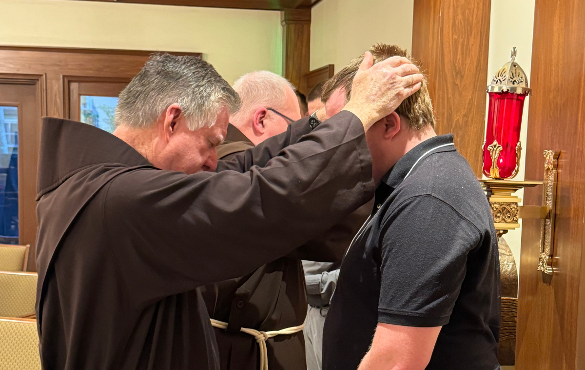 A friar prays over a discerner.