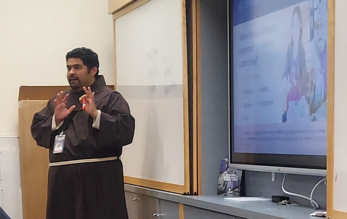 A friar teaches a classroom full of young adults