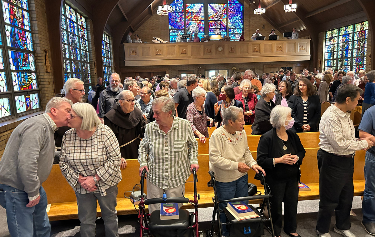 Parishioners share the sign of peace in the retreat house's church. The church is full