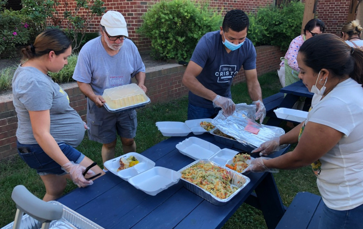 Volunteers fill takeaway boxes with pasta, bread and other food.