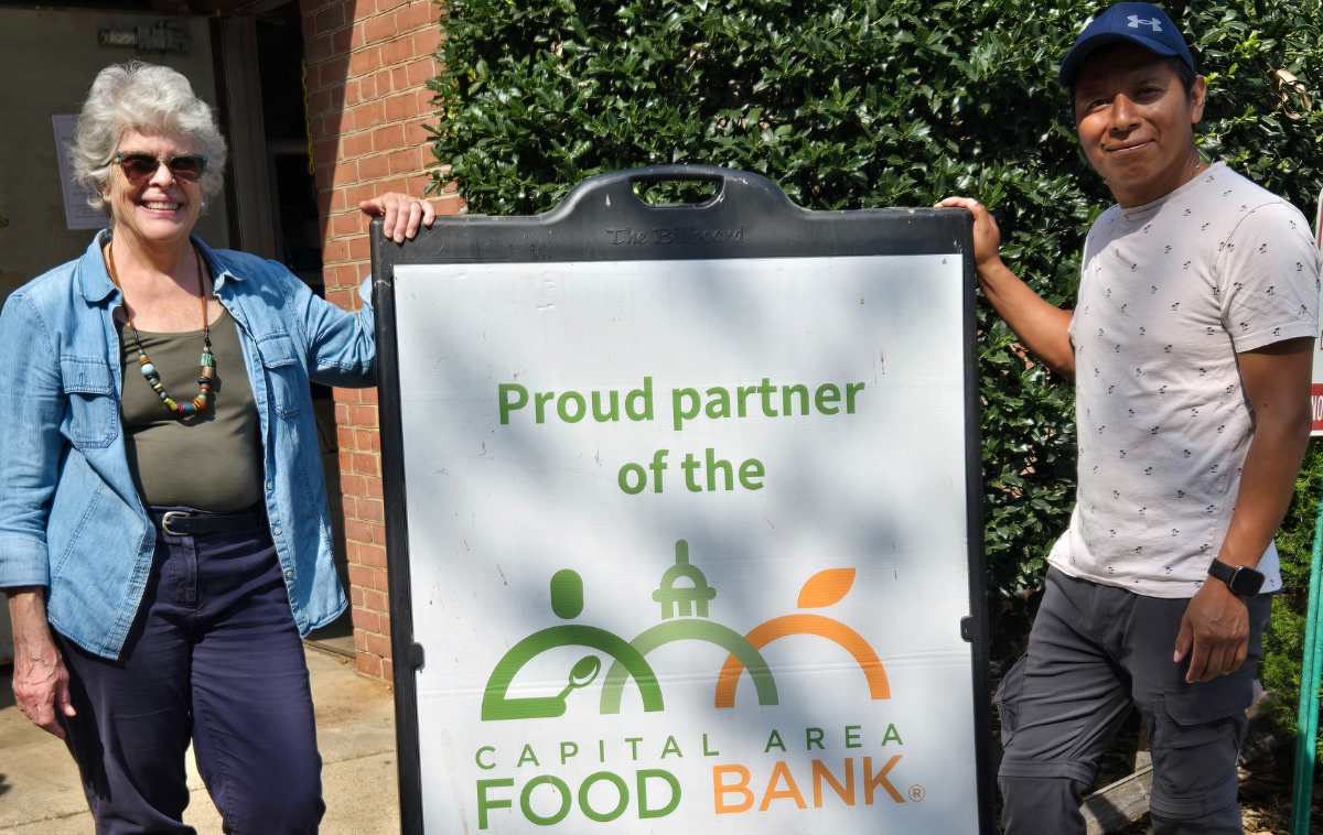 Two people stand next to a large sign that reads 