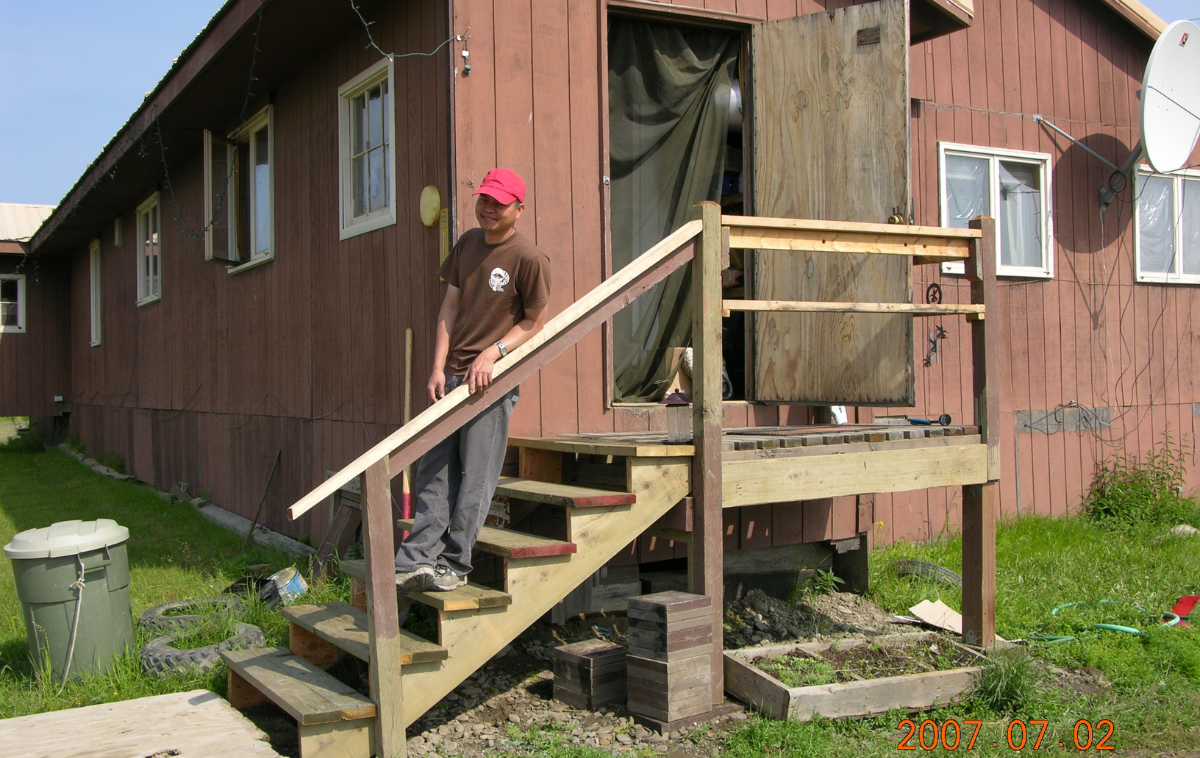 A man stands on the wooden steps in front of a church.