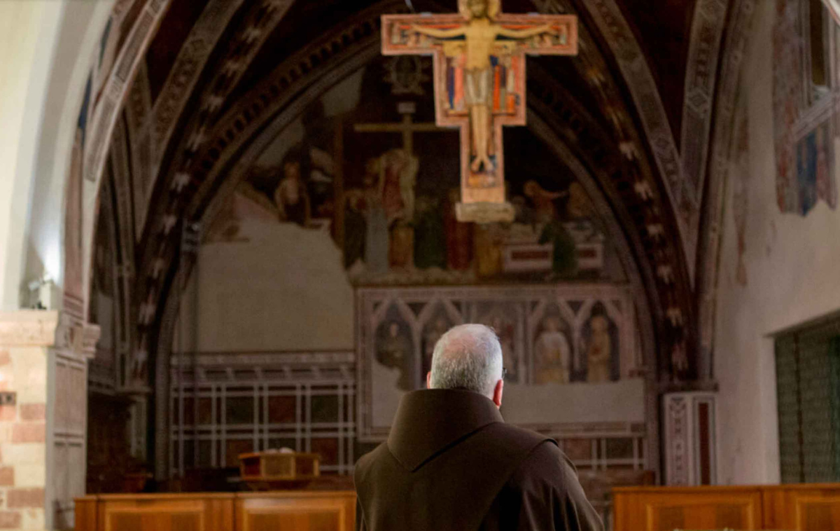 A friar prays in front of the San Damiano Cross