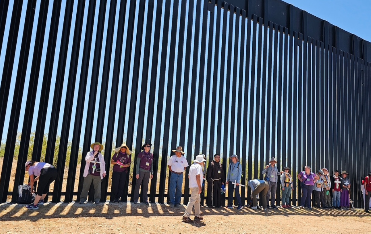 Participants in the Migrant Trail Walk gather along the wall separating the United States and Mexico. Postulant Francis Llamas said that he walked to better understand the experience of migrants. (Photo courtesy of Kevin Fox)