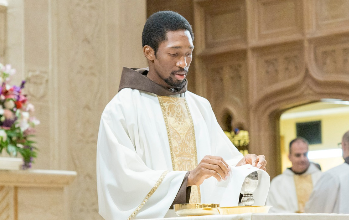 A man in a friar habit and vestments participates in Mass.